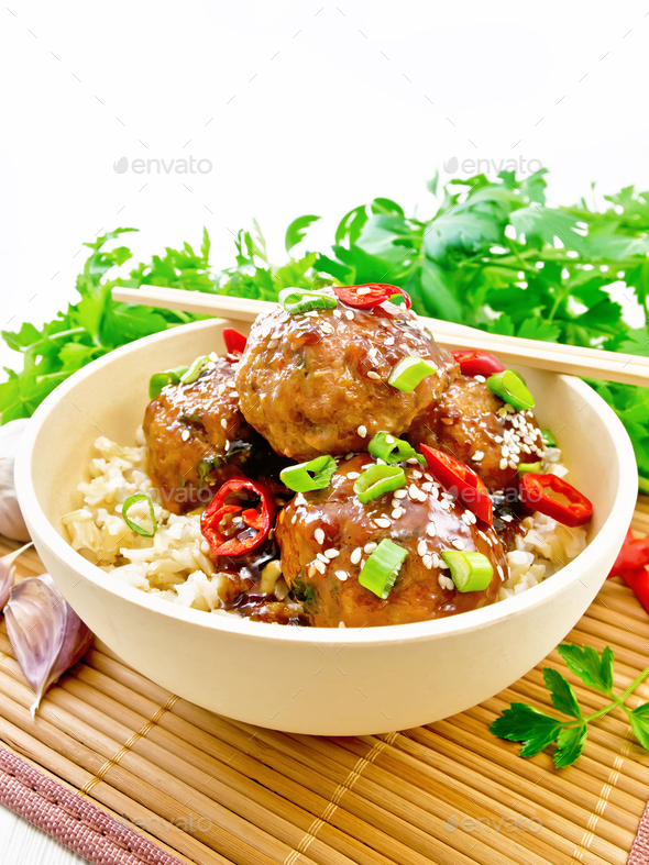 Meatballs in sweet and sour sauce with rice on board Stock Photo by rezkrr